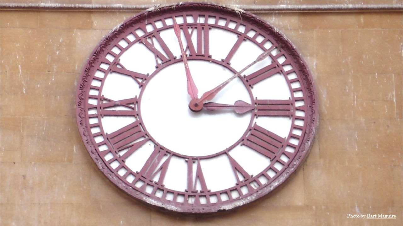 A clock on a building has two minute hands. One minute hand is eleven minutes slower than the other.